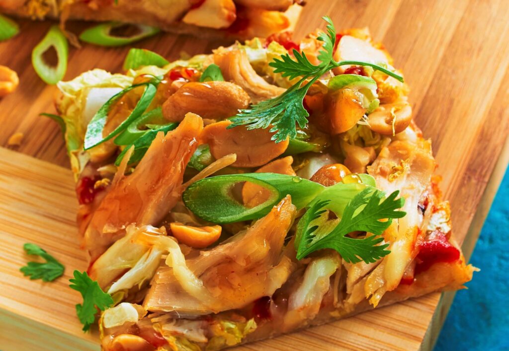 Eine selbstgemachte leckere Thai Chicken Pizza mit Erdnüssen zaubert tropisches Flair auf den heimischen Tisch ... und ist auch ideal fürs Mitnehmen geeignet.