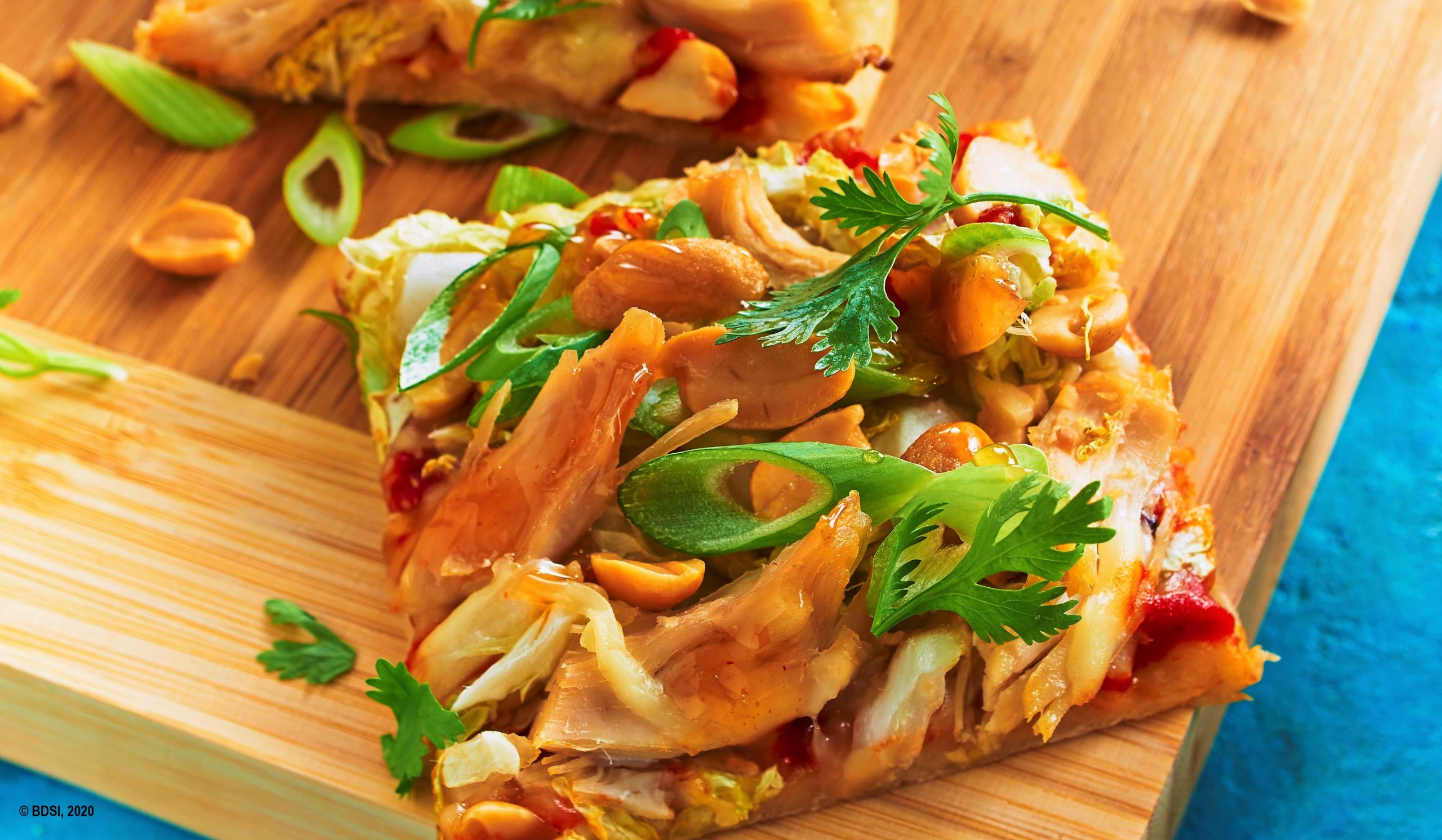 Eine selbstgemachte leckere Thai Chicken Pizza mit Erdnüssen zaubert tropisches Flair auf den heimischen Tisch ... und ist auch ideal fürs Mitnehmen geeignet.